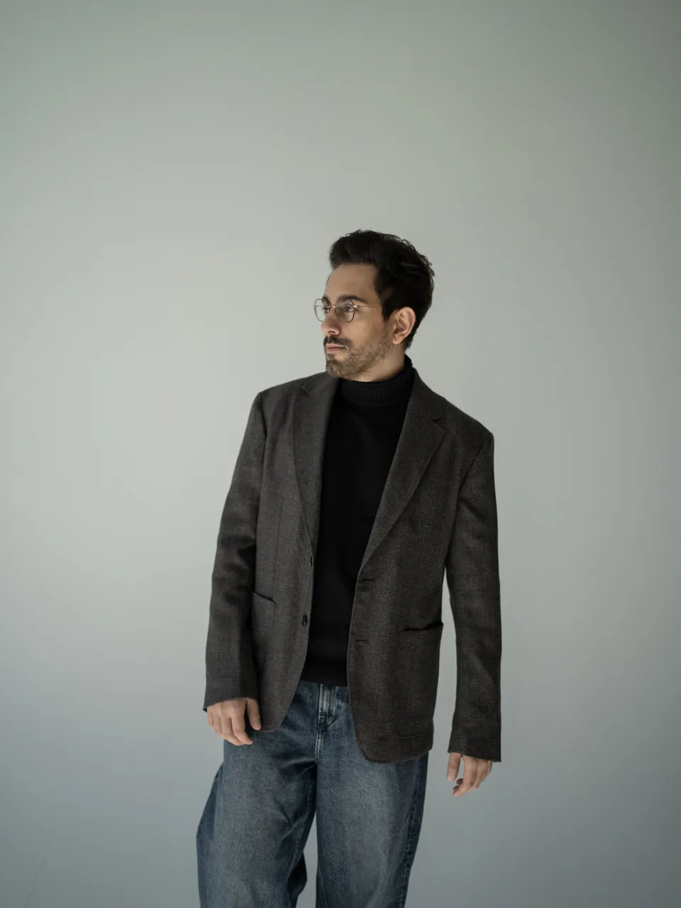 Bilal Khan standing in a black jacket and jeans in a portrait studio