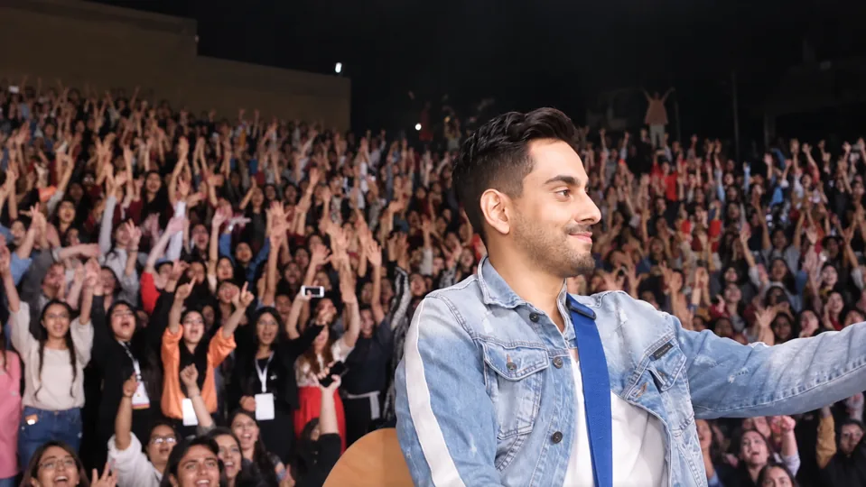 Bilal Khan on stage in front of an audience with raised hands